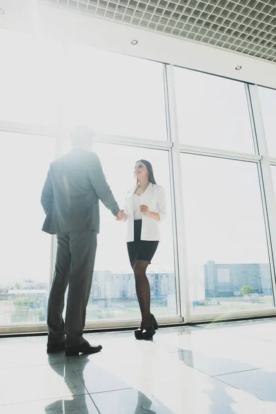 Negocios, trabajo en equipo, asociación, cooperación y concepto de personas - gente de negocios estrechando las manos sobre ventanas panorámicas de la oficina — Foto de Stock