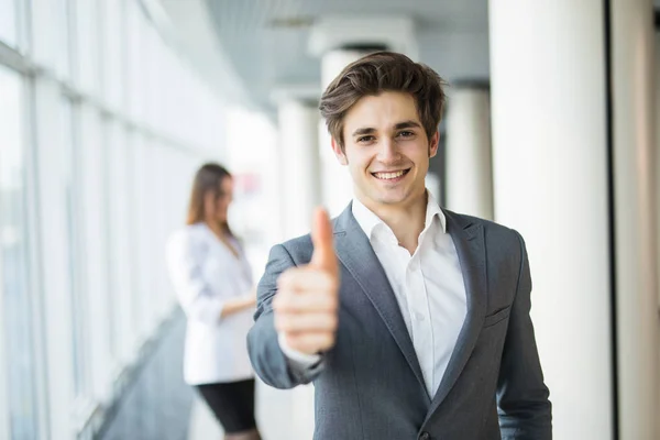 Jovem homem de negócios bonito polegares para cima na frente de mulher de negócios. Equipa empresarial — Fotografia de Stock