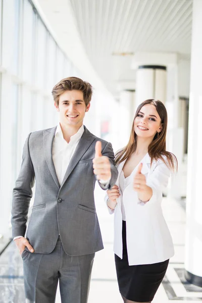 Motivated businessman and woman giving a thumbs up gesture of approval and success as they pose side by side giving the camera big friendly enthusiastic smiles — Stock Photo, Image