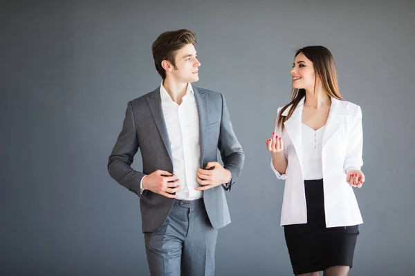 Empresária sorridente e empresário estão conversando contra fundo cinza. Conceito de negócio . — Fotografia de Stock