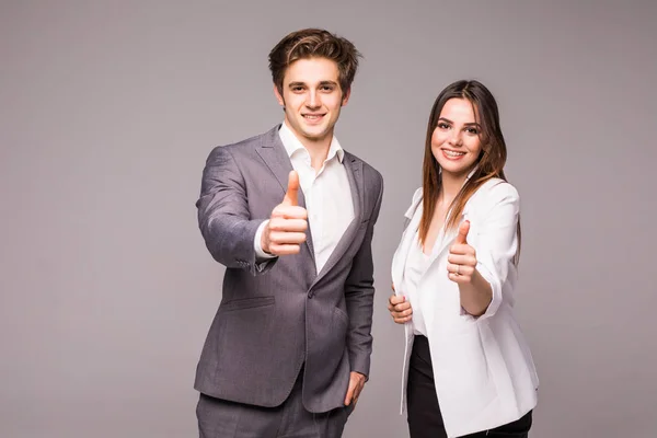 Dos felices hombres de negocios sonrientes en ropa formal mostrando pulgares hacia arriba sobre fondo gris — Foto de Stock