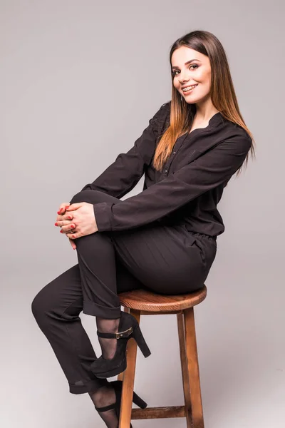 Volledige lengte portret van mooie vrouw zit op een stoel op grijs — Stockfoto