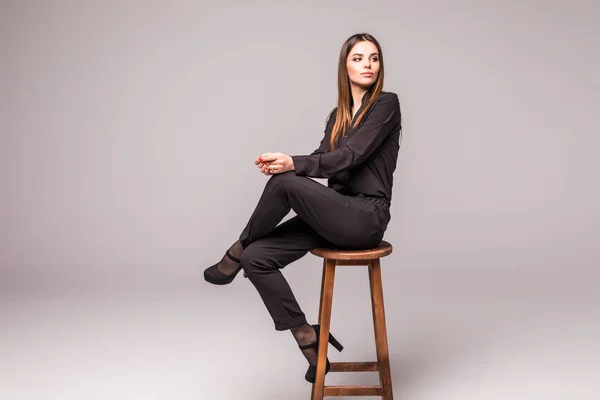 Szépség nő ül egy széken szürke háttér — Stock Fotó