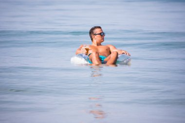 Adam okyanus su üzerinde lastik halka bira içip rahatlayın ve keyfini yaz meslek.
