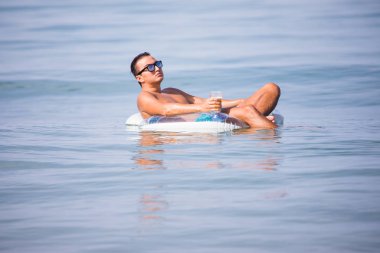 Adam okyanus su üzerinde lastik halka bira içip rahatlayın ve keyfini yaz meslek.