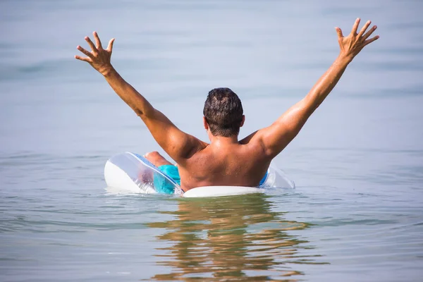Lykkelig ung mann med hevet hånd i havet ved sommerens kall – stockfoto