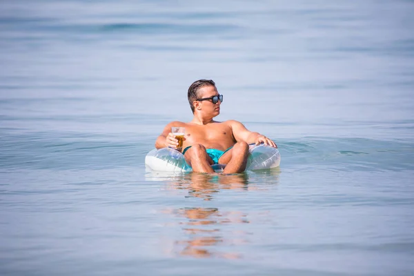 Мужчина отдыхает в океане воды на резиновом кольце пить пиво и наслаждаться летним призванием . — стоковое фото