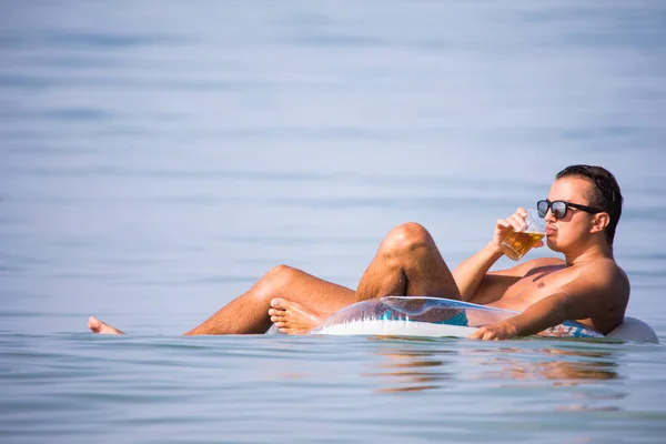 Handsome man swimming on rubber ring in sea with glass of beer enjoy summer vocation — Stock Photo, Image