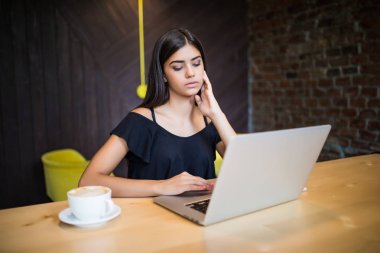 Güzel esmer kafede dizüstü bilgisayar kullanarak