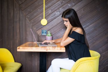 Yaratıcı office veya kafe pencere yanında otururken dizüstü bilgisayarda çalışan akıllı rahat kıyafet kendine güvenen genç kadın