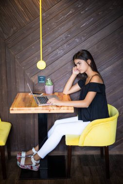 Yaratıcı office veya kafe pencere yanında otururken dizüstü bilgisayarda çalışan akıllı rahat kıyafet kendine güvenen genç kadın