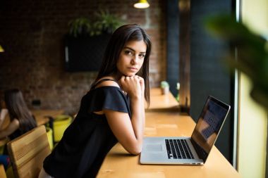 Yan görünümü. Kafe ve geçici notlar not defterinde masada oturan genç kadın. Çevrimiçi öğrenme. Öğrenci ödevi.