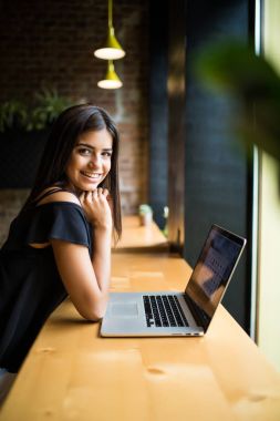 Yan görünümü. Kafe ve geçici notlar not defterinde masada oturan genç kadın. Çevrimiçi öğrenme. Öğrenci ödevi.