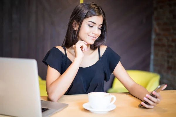 Elegant young smile woman with a laptop computer at a cafe using a mobile phone . — Stock Photo, Image