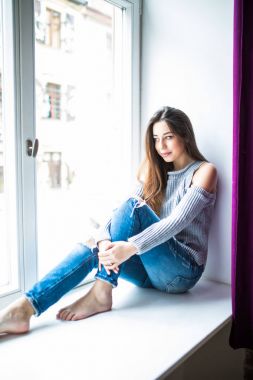 Pencere pervazına evde oturan güzel genç kadın