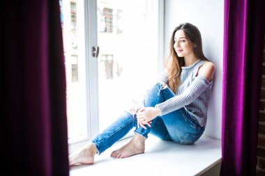 Pencere pervazına evde oturan güzel genç kadın