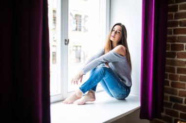 Büyüleyici güzellik. Güzel ve genç birbayan pencere evde otururken gülümseme ile seyir