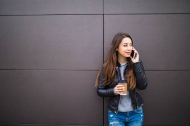 Gülümseyen kadın kahve ile telefonda duvar arka plan üzerinde söz