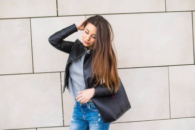 Genç kız duvar inşa çanta ile eğilerek gülümseyen