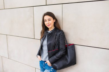 Genç kız duvar inşa çanta ile eğilerek gülümseyen