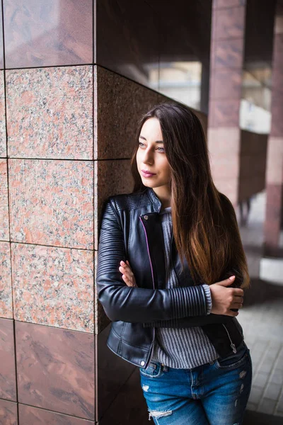 Porträtt av vackra unga kvinna som står mot en bakgrund av byggnader — Stockfoto