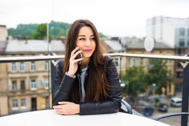 Genç sevimli Bayan kafe açık hava teras kahve yaparken onun akıllı telefonla konuşuyor.