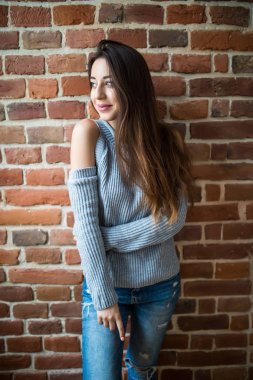 Kırmızı tuğla duvarın karşısında rahat genç ve güzel kadın