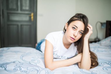 Kameraya bakarak ve evde yatakta yatıyordu süre gülümseyen genç kadın