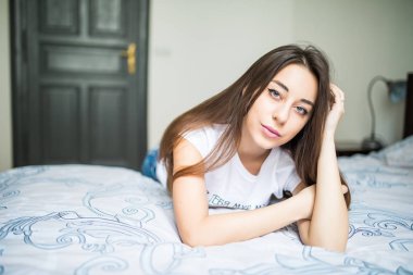 Kameraya bakarak ve evde yatakta yatıyordu süre gülümseyen genç kadın