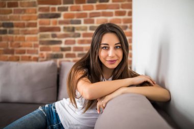 Koltukta yalan ve evde, rahat tarzı rahatlatıcı mutlu genç kadın