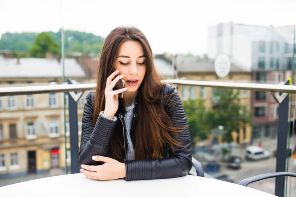 Joven linda dama está hablando en su teléfono inteligente mientras toma café en la terraza al aire libre de la cafetería . — Foto de Stock