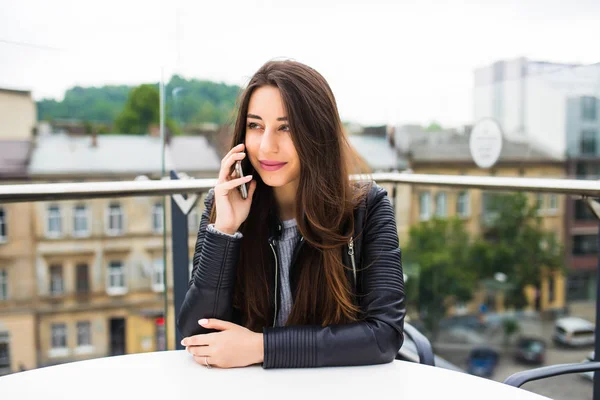 Retrato de una hermosa mujer joven en la terraza de la cafetería, relajante con teléfono inteligente, conversación telefónica al aire libre. Moda femenina utilizando la tecnología, sonriendo en el exterior de la ciudad, estilo de vida recreativo . — Foto de Stock
