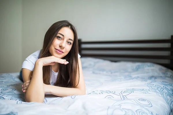 Portret piękna, młoda kobieta, leżąc na łóżku ręce na podbródek — Zdjęcie stockowe