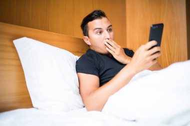 teknoloji, internet, iletişim ve insan kavramı - genç adam almak bir sms sürpriz haber ile evde yatakta sabah