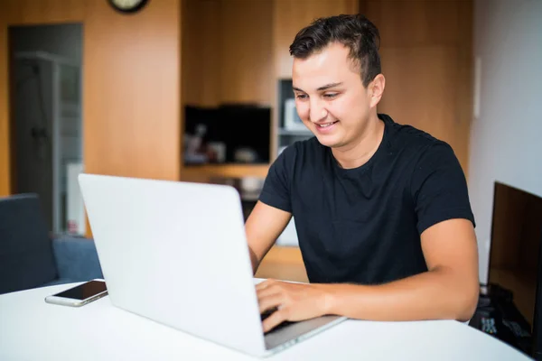 Hombre autónomo con sonrisa trabajando desde casa en el portátil — Foto de Stock