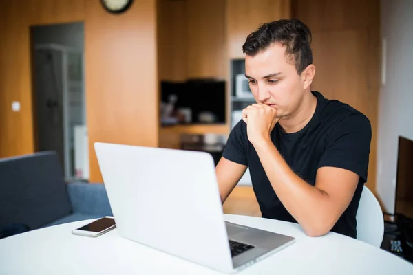 Empresario autónomo pensando y mirar trabajando desde casa en el ordenador portátil — Foto de Stock