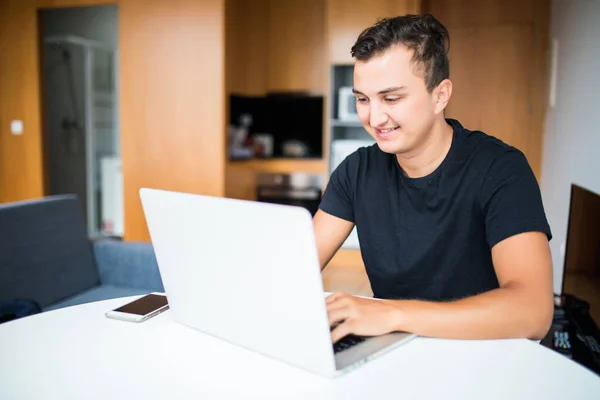 Hombre autónomo con sonrisa trabajando desde casa en el portátil — Foto de Stock