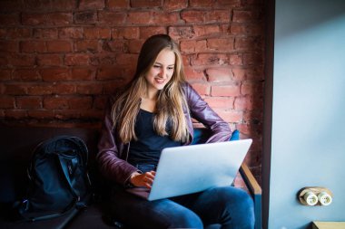Sevimli kız öğrenci kafe bar iç sabah kahvaltı sırasında otururken net-kitap kullanarak taşınabilir dizüstü bilgisayar, iş sırasında kahve keyfi bir genç güzel iş kadınları portresi