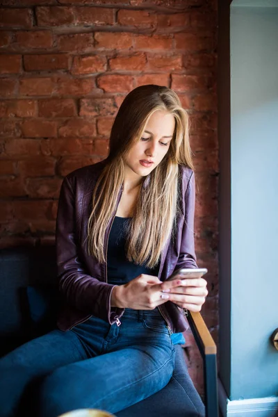 Güzel gülüşü olan, kafede dinlenirken cep telefonundan iyi haberler okuyan, Kafkasyalı mutlu bir kadın, boş zamanlarında cep telefonundan resimlerini seyrediyor.
