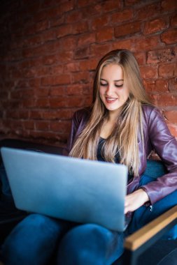 Dizüstü bilgisayar ile kafeteryada oturan serbest genç kadın