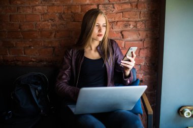 Mutlu girişimci bir telefon ve sokağın ortasında bir kafede dizüstü bilgisayar ile çalışma