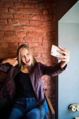 Neşeli kadın kendini bir arkadaşları ile sohbet, çekici gülümseyen hippi kız yapma kendi kendine portre cep telefonu akıllı telefon kamera kafede otururken fotoğraf çekimi sırasında poz