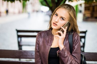 Mutlu kız cep telefonu sokakta bir bankta oturmuş: çağrı