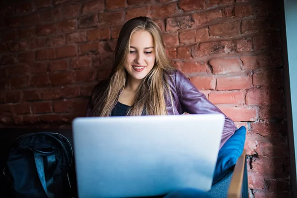 美しい若いフリーランスの女性がカフェのテーブルに座ってラップトップ コンピューターを使用して。幸せな笑顔の女の子オンラインでの作業や勉強ノートを使用しながら学習. — ストック写真