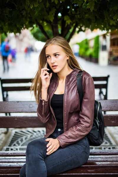 Mutlu kız cep telefonu sokakta bir bankta oturmuş: çağrı