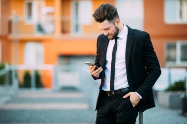 telefonunu kullanarak ve sokakta duran yakışıklı genç işadamı