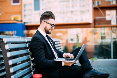 Onun bilgisayar ile çalışma ve üzerinde bir tezgah açık havada kahve içme işadamı