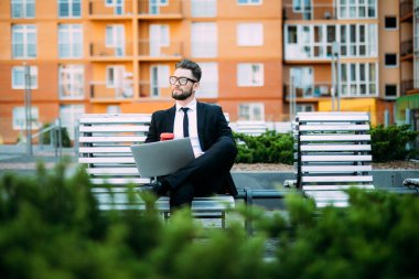 Onun bilgisayar ile çalışma ve üzerinde bir tezgah açık havada kahve içme işadamı