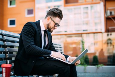 Onun bilgisayar ile çalışma ve üzerinde bir tezgah açık havada kahve içme işadamı