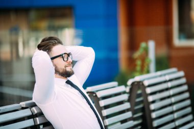 Rahat iş başının üzerine elle bir bankta oturan adam ve başarıdan sonra serbest zaman zevk